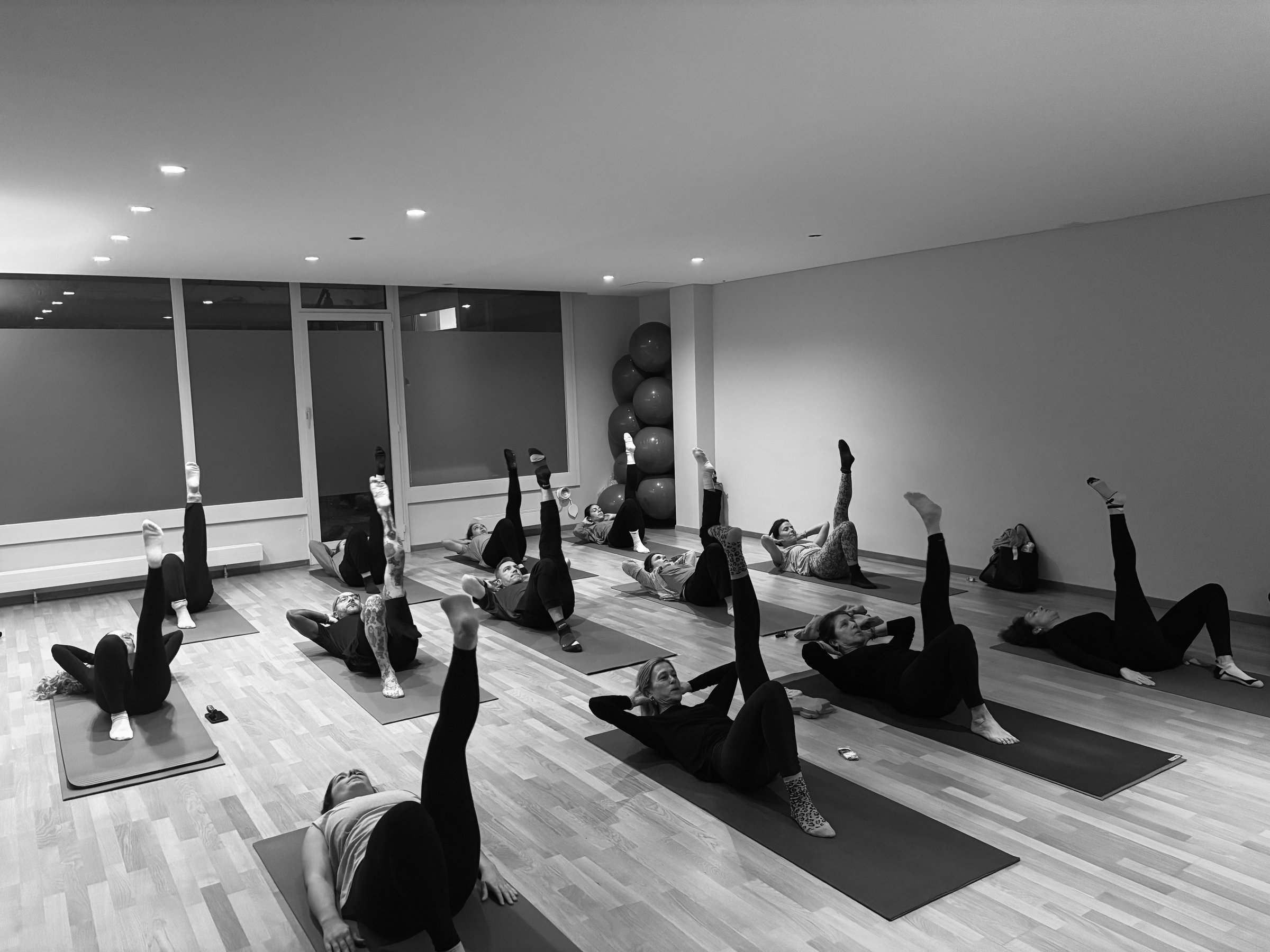 Cours collectif sur tapis, les participantes lèvent une jambe tendue